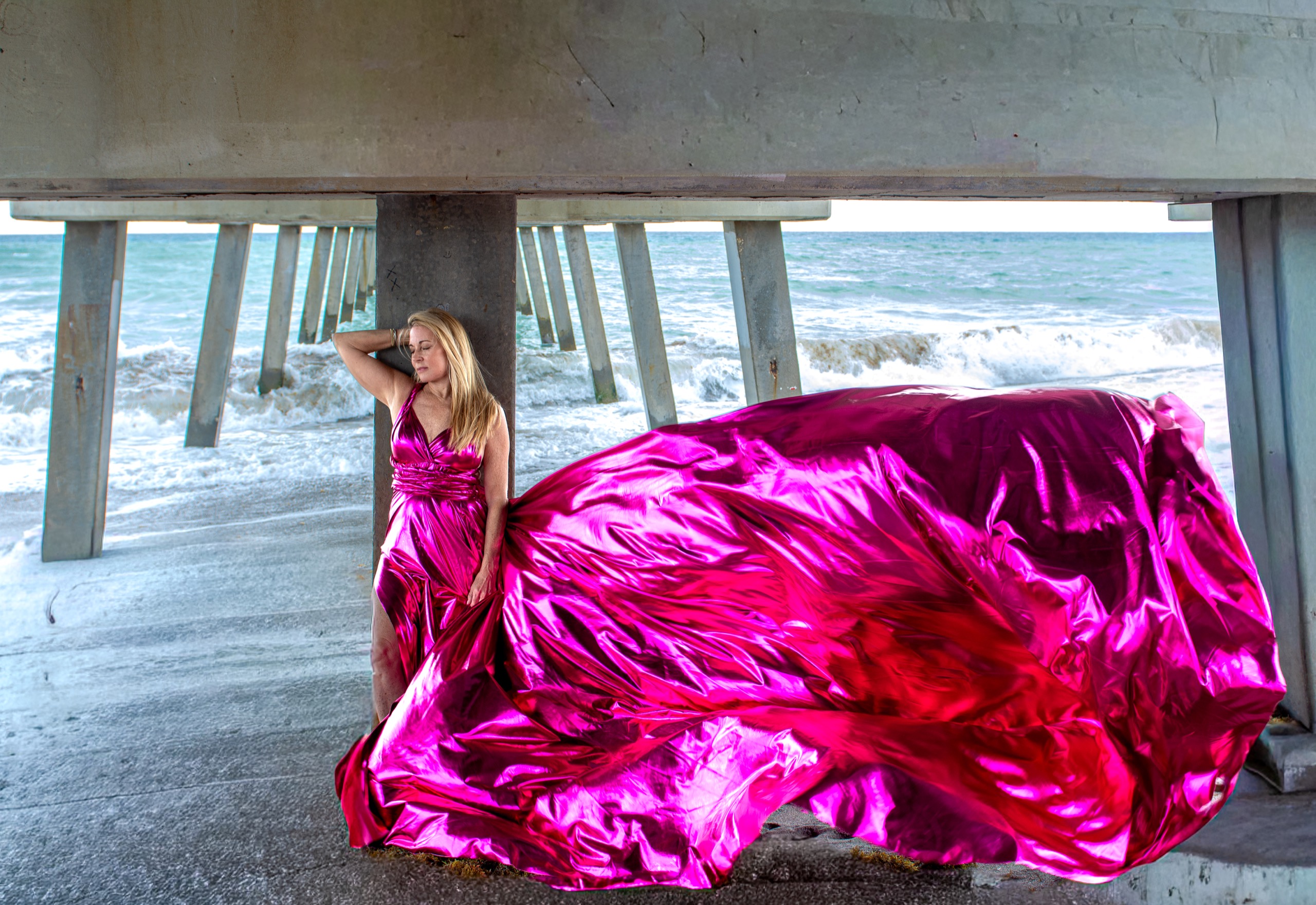 Flying dress photoshoot on the beach — metallic pink gown billowing in the wind