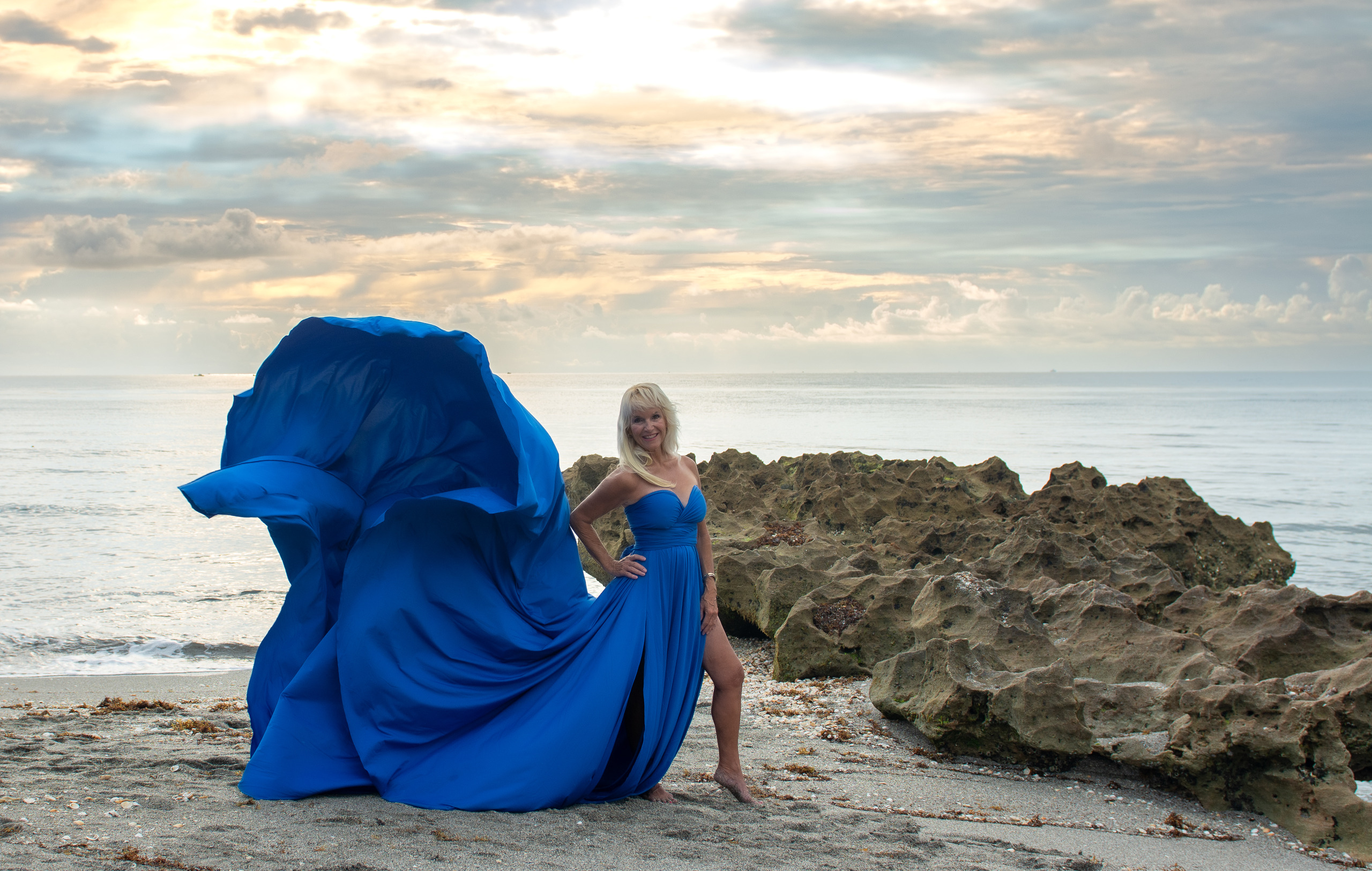 Flying dress photoshoot at sunrise on the rocks — royal blue gown