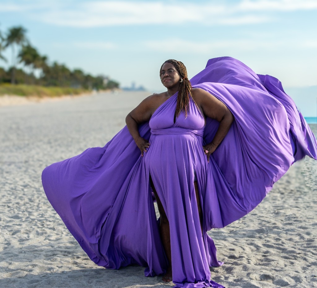 Flying dress photoshoot on the beach — purple gown billowing against the skyline